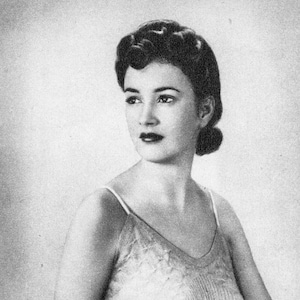 Puede incluir: Un bañador de una pieza de estilo vintage con una falda texturizada con estampado de diamantes y un corpiño acanalado. El bañador tiene tirantes finos y un escote en V. La modelo tiene el pelo oscuro y mira hacia un lado.