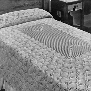 May include: A white, intricately patterned bedspread and pillowcase set. The bedspread features a repeating, stylized leaf design, with a central geometric pattern. The bedding is placed on a bed with a wooden headboard and a nightstand.