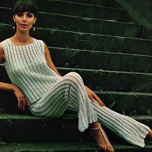 Peut inclure: Ensemble blanc sans manches en crochet, composé d'un haut et d'un pantalon assortis. Le motif ajouré crée un aspect texturé. La tenue est portée sur des marches en béton vert foncé. Le haut a une encolure carrée.