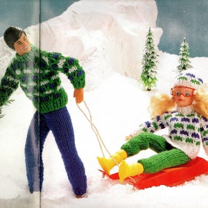 Puede incluir: Dos muñecos en la nieve. Uno tira del otro en un trineo rojo. Ambos muñecos visten conjuntos de punto en verde, blanco y azul. El muñeco del trineo lleva un gorro a juego y botas amarillas.