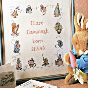 May include: A white ceramic mug with a black handle and the text "But First, Coffee" in a bold, black font. The mug is set against a blurred background, suggesting a cozy setting.