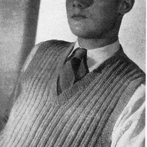 May include: A black and white photograph showing a sleeveless V-neck sweater vest with a vertical ribbed knit pattern. The garment is worn over a collared button-down shirt and a dark necktie, featuring a textured knit construction throughout.
