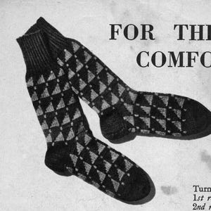 Puede incluir: Un par de calcetines negros y grises con un diseño de rombos. Los calcetines son de punto y se muestran sobre un fondo blanco. El texto "FOR THE COMFORT" es visible en el fondo.