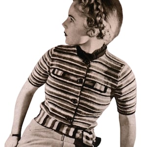 Może przedstawiać: Sweter w stylu vintage z krótkim rękawem i poziomymi paskami w odcieniach brązu, szarości i bieli. Sweter ma zapinany na guziki przód, dwie małe kieszenie i ciemny kołnierz. Osoba ma na sobie jasne spodnie.