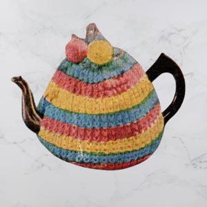 Könnte beinhalten: Eine farbenfrohe Teekanne mit einem gestrickten Überzug. Der Überzug hat horizontale Streifen in Rot, Gelb, Blau und Rosa. Ausguss und Henkel sind dunkelbraun, und der Deckel hat einen rosa und gelben Akzent. Die Teekanne steht vor einem weißen Marmorhintergrund.