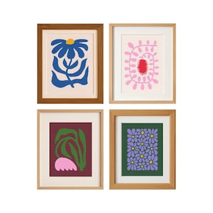 May include: Four framed art prints with vibrant floral designs. The prints showcase a blue flower, a pink spiral, green leaves with a pink shape, and purple flowers. Each print is in a wooden frame, creating a cohesive gallery wall aesthetic.