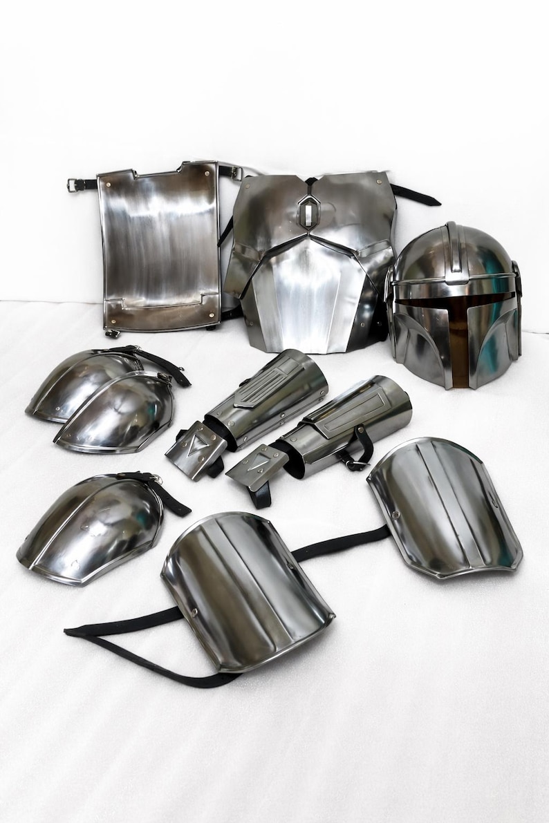 Puede incluir: Un conjunto de piezas de armadura plateadas y brillantes, que incluyen un casco, una placa para el pecho, hombreras y protectores de brazos. La armadura parece estar hecha de metal y est&aacute; dise&ntilde;ada con una est&eacute;tica futurista. Las piezas est&aacute;n dispuestas sobre una superficie blanca.