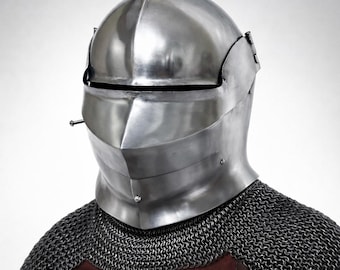 May include: A polished steel knight helmet with a visor and a riveted construction. The helmet is shown over a chainmail coif and a red leather garment. The text on the image reads "18 Gauge Steel Knight Helmet".