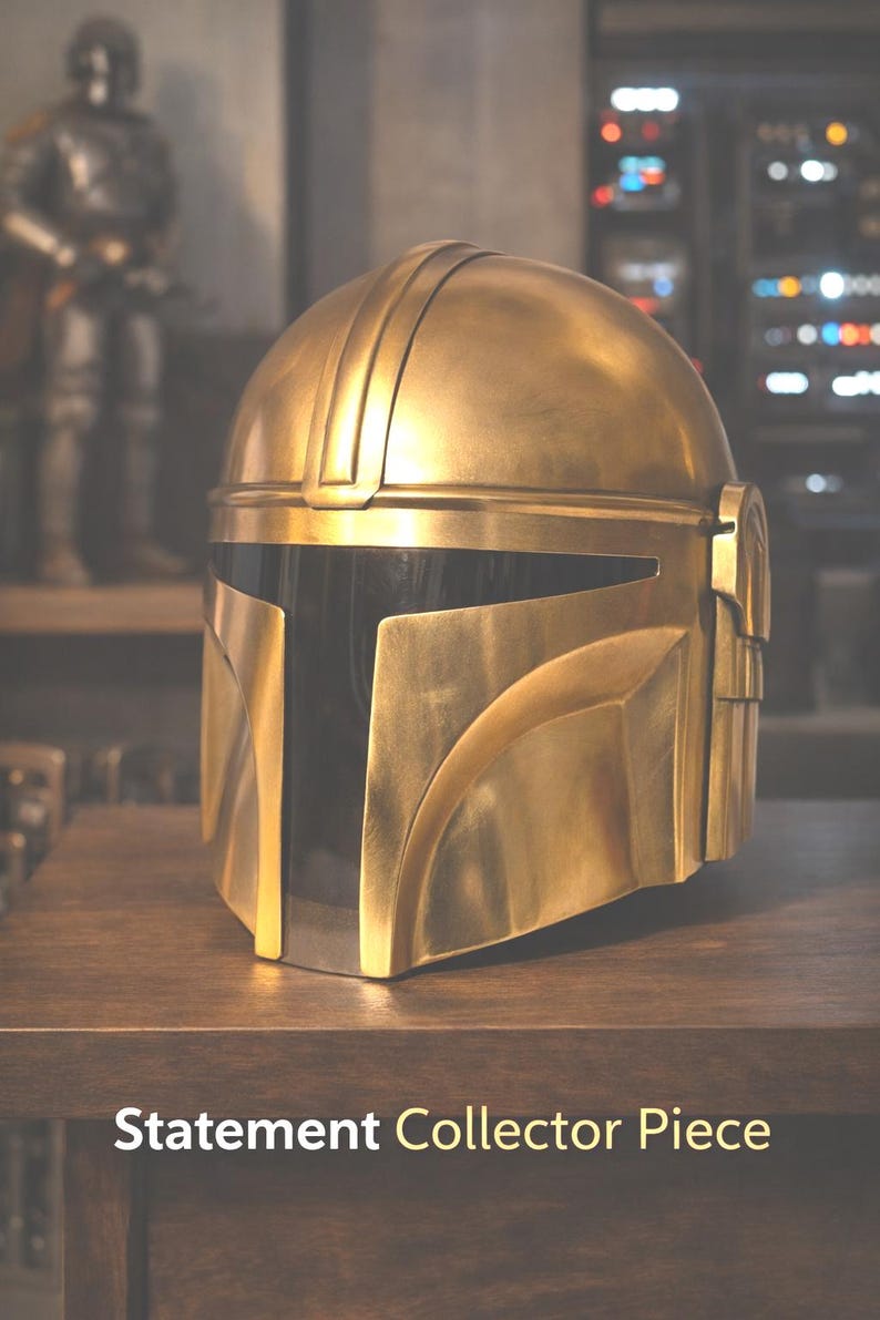 May include: A gold-colored helmet with a black visor, resting on a wooden surface. The helmet has a smooth, metallic finish and is designed with angular shapes. The text "Statement Collector Piece" is displayed at the bottom.