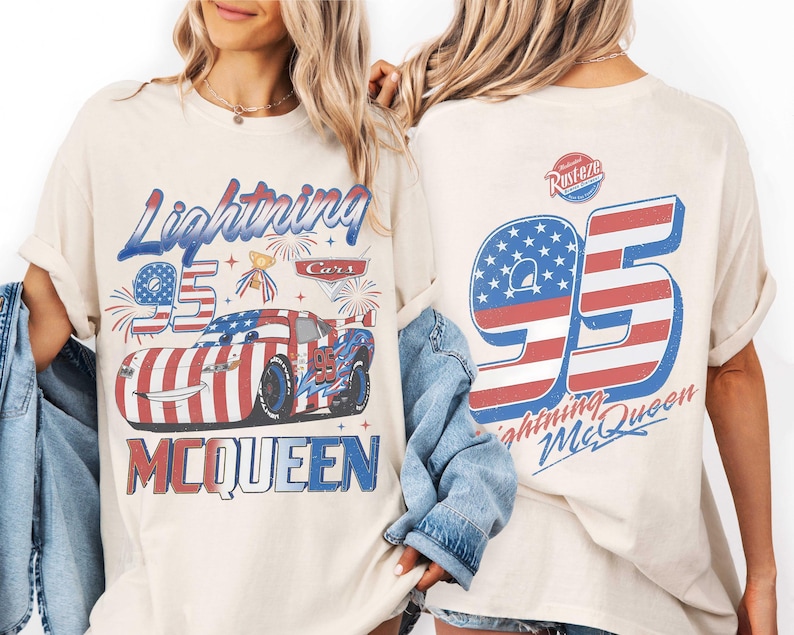 Może przedstawiać: Kremowy t-shirt z grafiką Lightning McQueen w motywy flagi amerykańskiej, numerem 95 i napisem Lightning McQueen. Z tyłu znajduje się duża liczba 95 z pasami flagi oraz logo Rust-eze w kolorze czerwonym i niebieskim.