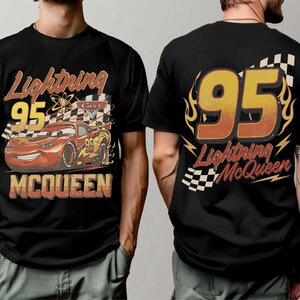 May include: Black t-shirt with a Lightning McQueen design. The front shows the number 95, a chequered flag, and the text "Lightning McQueen." The back of the shirt also features "95" and "Lightning McQueen" with flame and lightning bolt details.