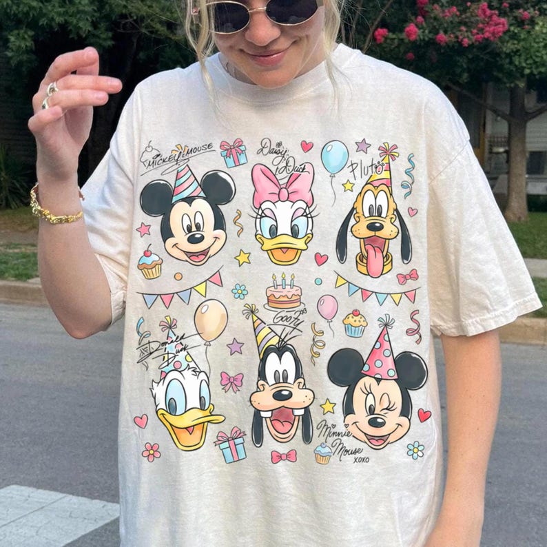 Puede incluir: Camiseta de color crema con los personajes de dibujos animados Mickey Mouse, Daisy Duck, Pluto, Donald Duck, Goofy y Minnie Mouse. El dise&ntilde;o incluye gorros de fiesta, globos, magdalenas y el texto "Mickey Mouse" y "Daisy Duck".