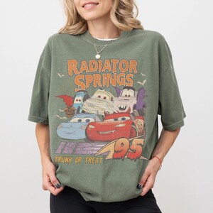 May include: Green t-shirt featuring a graphic of characters from the movie Cars, with the text "Radiator Springs" and "Trunk or Treat". The graphic includes the number "95".