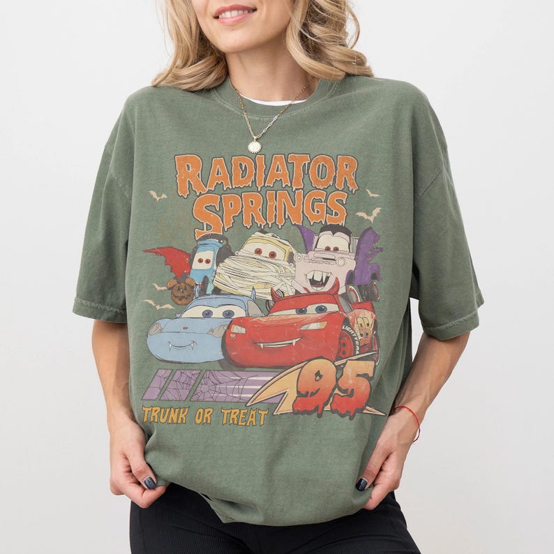May include: Green t-shirt featuring a graphic of characters from the movie Cars, with the text "Radiator Springs" and "Trunk or Treat". The graphic includes the number "95".