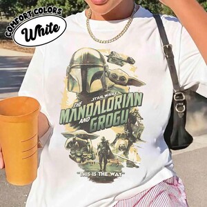 K&ouml;nnte beinhalten: Wei&szlig;es T-Shirt mit einem Grafikdesign aus der Star Wars-Serie "The Mandalorian and Grogu". Das Design zeigt den Mandalorianer, Grogu und ein Raumschiff mit dem Satz "This is the Way."
