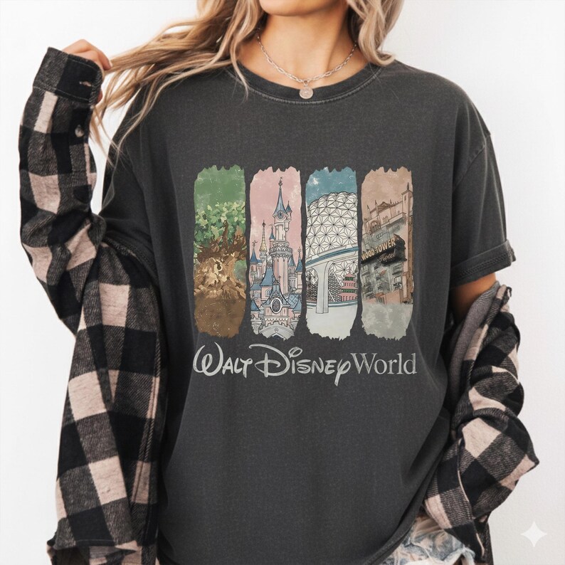 May include: Dark gray t-shirt featuring a colorful graphic of Walt Disney World landmarks. The design includes images of the Tree of Life, Cinderella Castle, Spaceship Earth, and Tower of Terror. The words "Walt Disney World" are printed below the graphic.