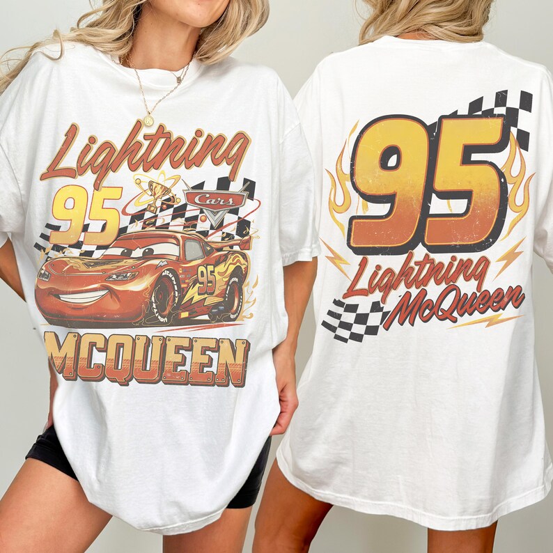 May include: White t-shirt with a graphic of Lightning McQueen from the Cars film. The front design includes McQueen, the number 95, and a checkered flag. The back features a large "95" and the words "Lightning McQueen".