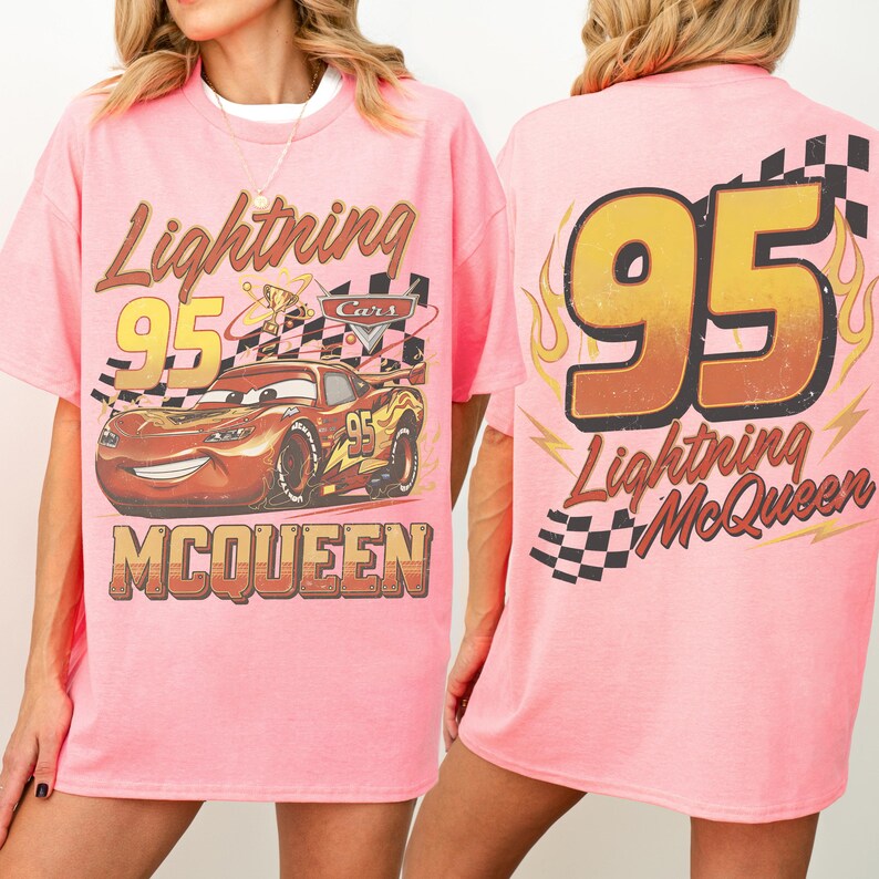 May include: Pink t-shirt with a Lightning McQueen graphic from the Cars film. The front shows the character, number 95, and "Lightning McQueen". The back has a large "95" with flames and "Lightning McQueen".