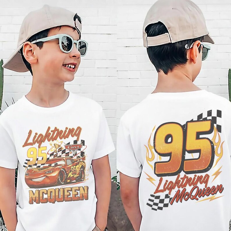 May include: White t-shirt featuring Lightning McQueen from the Cars movie. The front of the shirt displays the character with the text "Lightning 95 McQueen". The back of the shirt has a large "95" with flames and the text "Lightning McQueen".