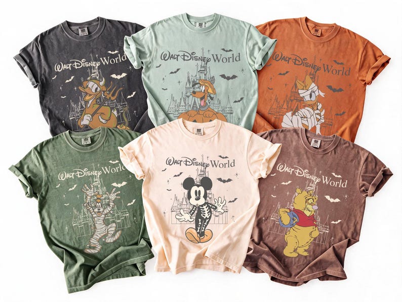 May include: Six vintage-style t-shirts in various colours, each featuring a Disney character in a Halloween costume with the text "Walt Disney World". The shirts are in shades of grey, green, orange, and beige.