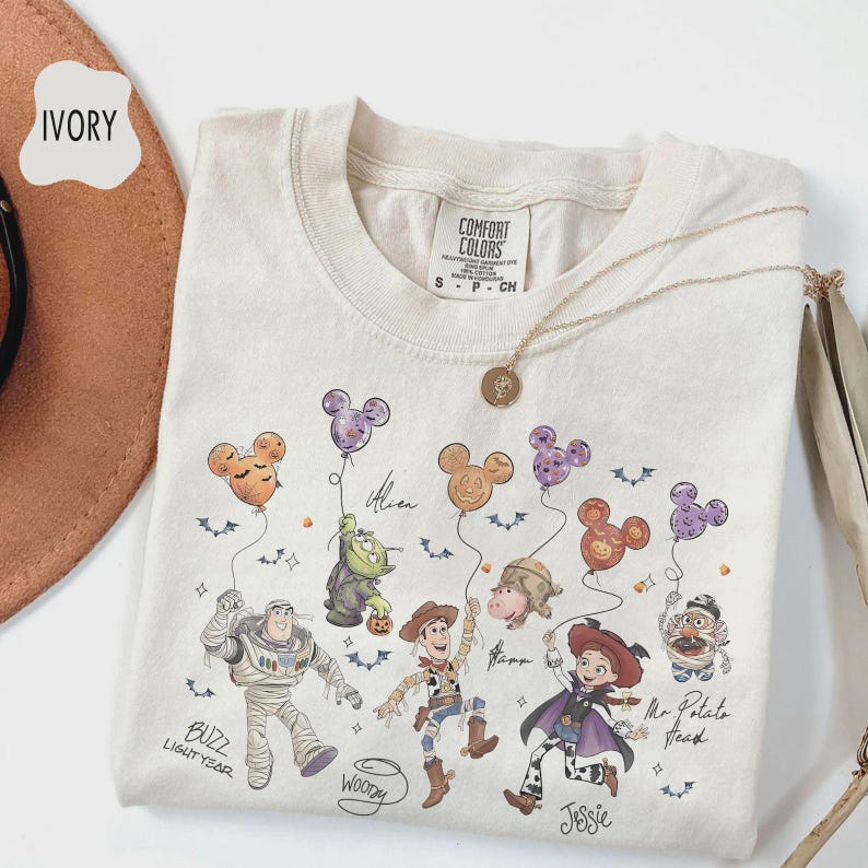 Puede incluir: Camiseta Comfort Colors de color marfil con un gr&aacute;fico de personajes de Disney sosteniendo globos con forma de Mickey Mouse. Los personajes incluyen a Buzz Lightyear, Woody y Jessie. La camiseta tiene cuello redondo y mangas cortas.