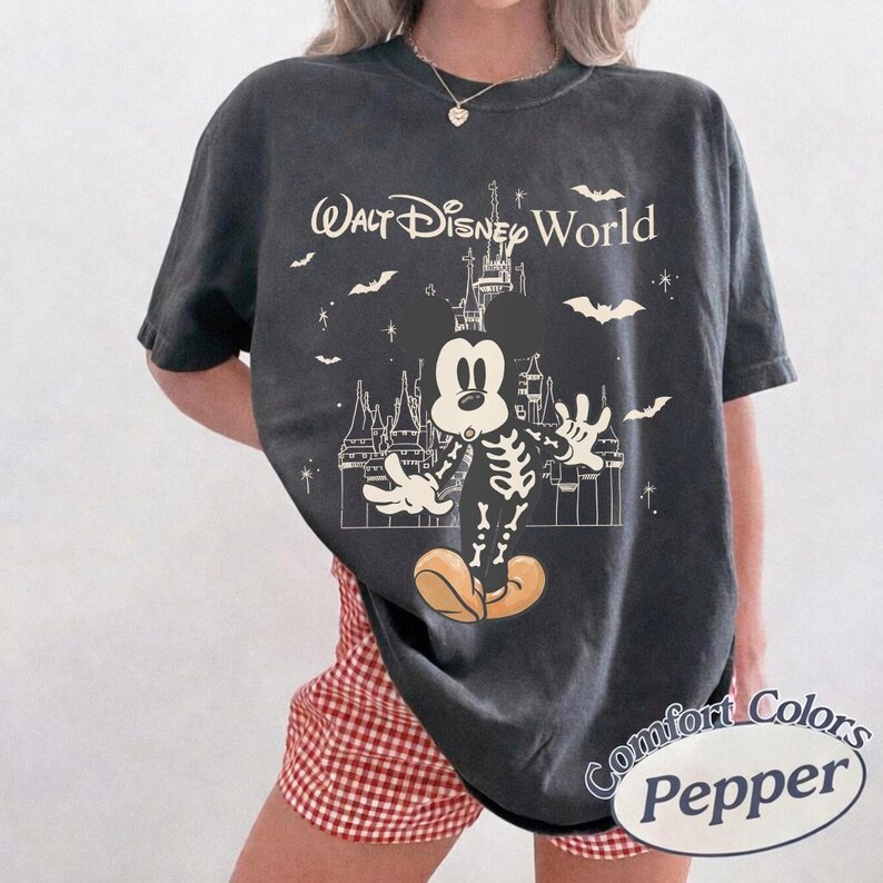 May include: Dark grey t-shirt with a Halloween Mickey Mouse design. The graphic shows a skeleton Mickey, bats, and the words "Walt Disney World." The shirt has a vintage appearance and a Comfort Colors Pepper label.