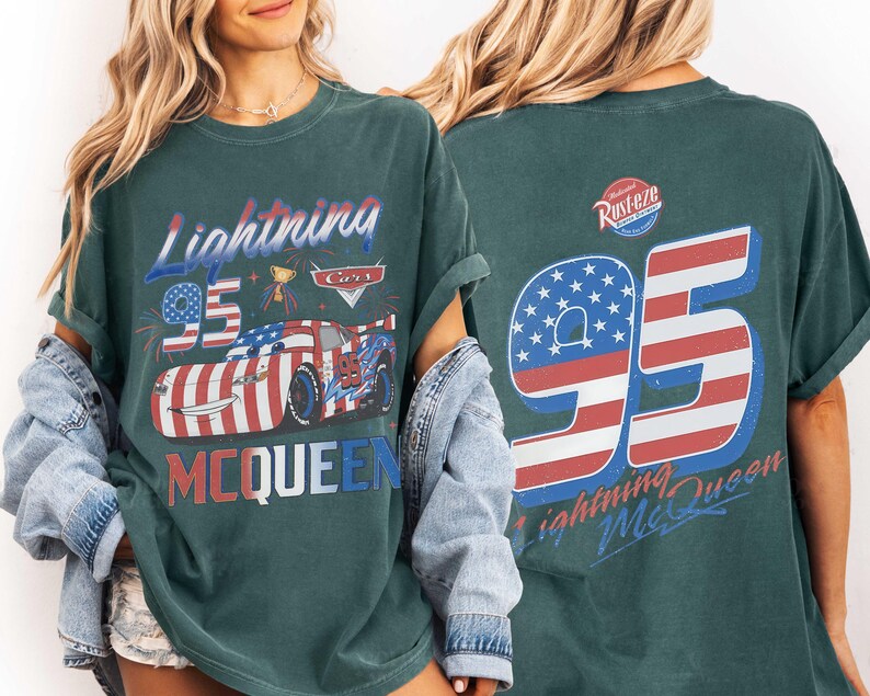 Może przedstawiać: Ciemnozielono-niebieski t-shirt z grafiką przedstawiającą Lightning McQueen z filmu Cars z przodu oraz napisem Lightning McQueen i 95. Z tyłu znajduje się duża liczba 95 w barwach flagi USA, logo Rust-eze oraz napis Lightning McQueen.