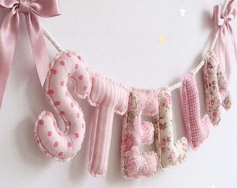 Striscione personalizzato con il nome del bambino, lettere in tessuto imbottito, decorazione murale per cameretta dai colori pastello.