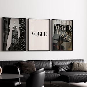 Könnte beinhalten: Drei gerahmte Kunstdrucke hängen an einer weißen Wand über einem schwarzen Ledersofa. Die Drucke zeigen ein Schwarz-Weiß-Foto des Empire State Building, das Wort "VOGUE" und ein Vogue-Magazin-Cover.