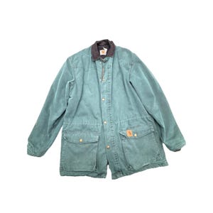 May include: A teal-colored work jacket with a brown corduroy collar. The jacket has four front pockets, a button-up closure, and a small logo patch on one pocket. The jacket is made of a durable, heavy-duty material.
