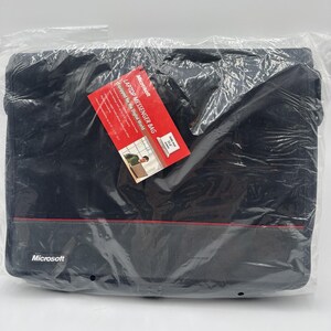 May include: A black Microsoft laptop messenger bag enclosed in clear plastic packaging. A red product tag is attached, featuring the text "Microsoft LAPTOP MESSENGER BAG Equipped for the Digital World" and "Fits most 15.4" screens". The bag has a thin red horizontal line.