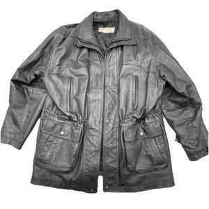 May include: A black leather jacket with a collared neckline, zipper closure, and multiple pockets. The jacket features a drawstring waist and a small label near the collar. The jacket is a classic outerwear piece.