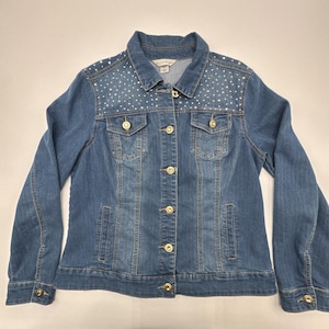 May include: A medium-wash denim jacket with a collared neckline and long sleeves. The jacket features gold-colored buttons and is embellished with small, sparkling rhinestones on the shoulders. A classic, stylish outerwear piece.