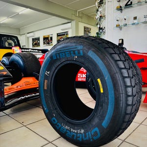 May include: A black Pirelli Cinturato wet racing tire featuring blue lettering on the sidewall. The tire displays the text Pirelli, Cinturato, and #18 Bar Wet, with a yellow warning label visible on the tread surface of the rubber tire.