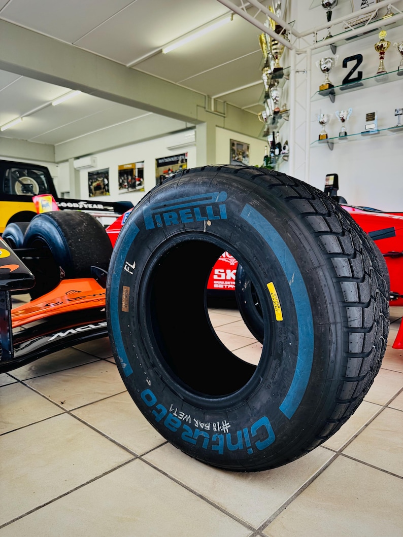 May include: A black Pirelli Cinturato wet racing tire featuring blue lettering on the sidewall. The tire displays the text Pirelli, Cinturato, and #18 Bar Wet, with a yellow warning label visible on the tread surface of the rubber tire.