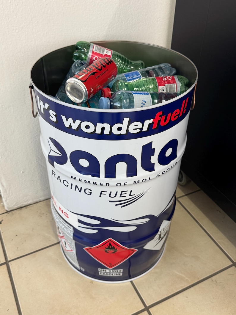 May include: A white and blue metal barrel filled with plastic water bottles and a red soda can. The barrel has the text "It's wonderful! Panta Racing Fuel" printed on it. A red and white hazard label is visible.
