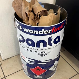 May include: A white and blue Panta Racing Fuel drum filled with brown paper and cardboard. The drum has a red hazard symbol and the text "It's wonderfuel!" and "Racing Fuel".