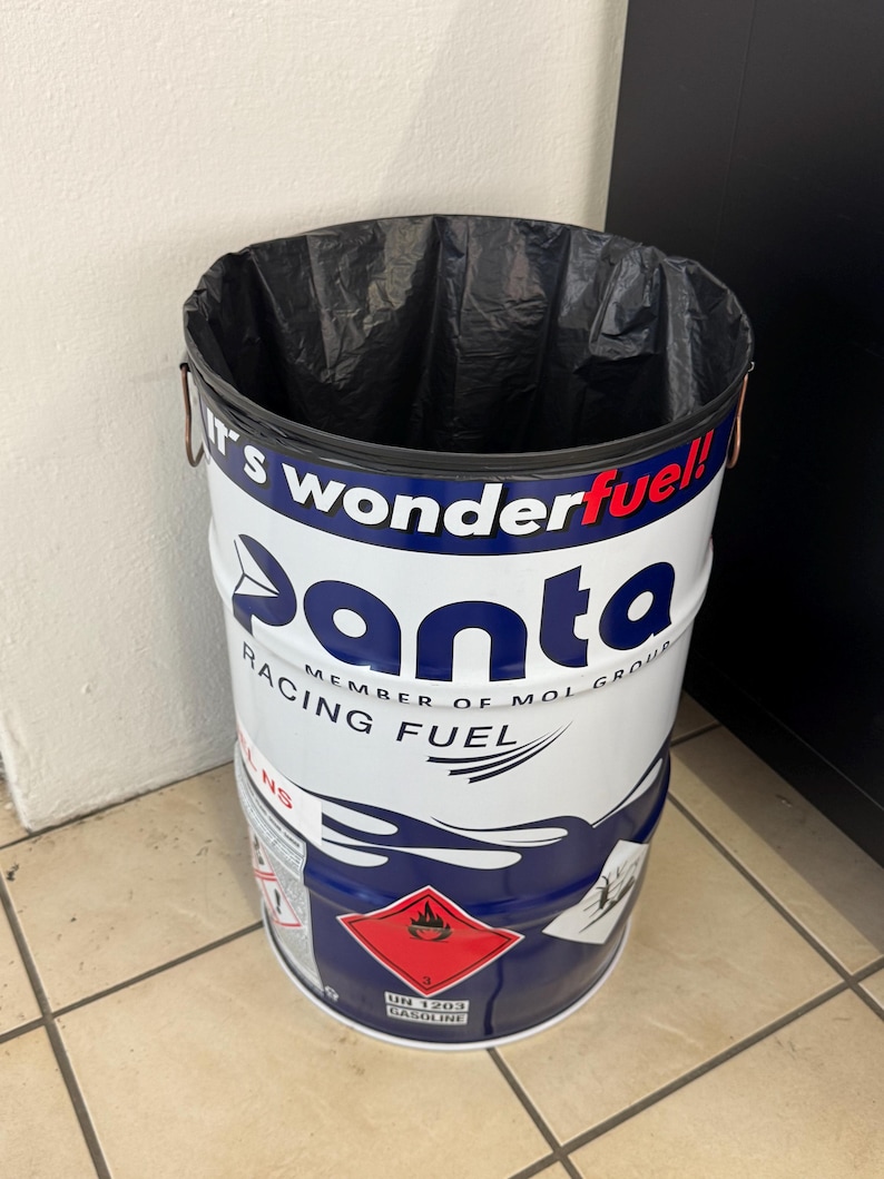 May include: A cylindrical metal trash can with a black plastic liner. The can is white with blue and red graphics, including the word "panta" and "RACING FUEL." A red diamond hazard symbol is visible.