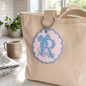 Etiqueta de bolsa personalizada com bordado xadrez vichy: chaveiro com monograma personalizado, laço rosa com borda ondulada.