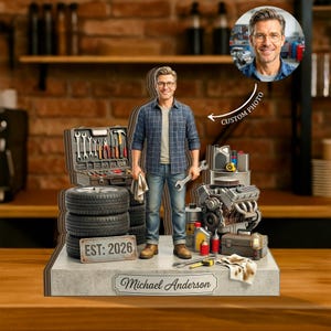 May include: A personalised garage-themed figurine depicting a man in a blue plaid shirt and jeans, holding a wrench and a rag. The base includes a toolbox, tyres, engine, and the text "EST: 2026" and "Michael Anderson". A custom photo is also included.