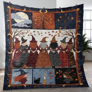 May include: A quilted blanket featuring a design with witches holding hands, a cauldron, and the text "girls will be girls." The blanket has a dark blue border with moons and stars, and a central panel with a full moon and trees.