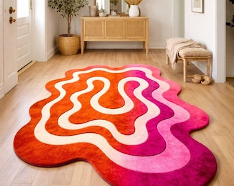 May include: A vibrant, abstract rug with a unique, flowing design. The rug features a blend of colors, including shades of orange, pink, and white. Its irregular shape and bold color palette make it a statement piece for any room.