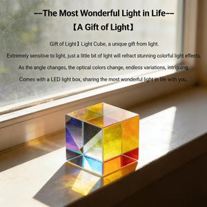 Può includere: Un cubo di luce geometrico e colorato con il testo "La luce più meravigliosa della vita" e "Un dono di luce". Il cubo è fatto di vetro trasparente sfaccettato, che riflette uno spettro di colori. È appoggiato su un davanzale.