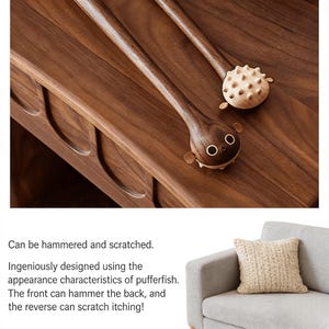 May include: Two wooden massage tools with long handles and pufferfish-shaped heads. One has a smooth, rounded head with two eyes and small fins. The other has a spiky head. The tools are on a wooden surface.