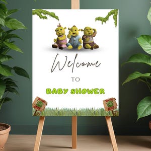 May include: A wooden easel displaying a white sign with the words "Welcome to Baby Shower." The sign features cartoon characters and decorative elements. Two small wooden signs with the words "Beware Ogre" are at the bottom.