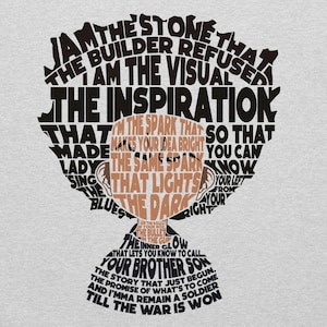 May include: A light gray t-shirt featuring a graphic design of a person's head composed of text. The text includes phrases like "The Stone That The Builder Refused" and "The Inspiration". The design is in black and brown.