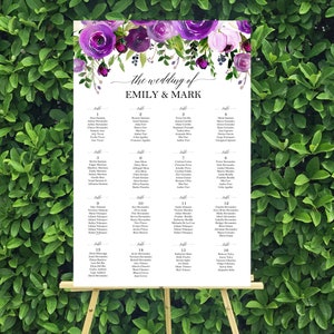 May include: A wedding seating chart with a floral design featuring purple and pink flowers. The chart lists the names of guests assigned to each table. The text at the top reads "The wedding of Emily & Mark".