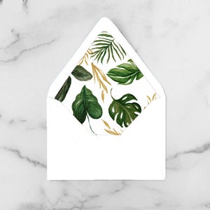 May include: A white envelope with a tropical leaf pattern on the inside. The pattern features green and gold leaves on a white background. The envelope is open, revealing the interior design.
