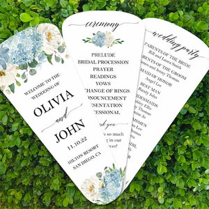 May include: Wedding ceremony program fan with blue and white floral design. The front features the names Olivia and John, the date 11.10.22, and the location Hilton Resort, San Diego, CA. The back includes the ceremony order and the wedding party.