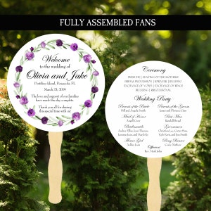 May include: A white wedding fan with a purple floral wreath and the text "Welcome to the wedding of Olivia and Jake" and the wedding date. The back of the fan lists the wedding party and ceremony details.